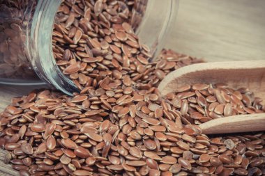 Tahta kaşıkla besin lifleri ve doğal mineraller içeren keten tohumu yığını. Besleyici yiyecekler.