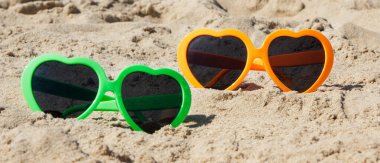 Kumsalda kumsalda renkli güneş gözlükleri. Güneş banyosu sırasında güneş koruması. Seyahat ve tatil zamanı kavramı