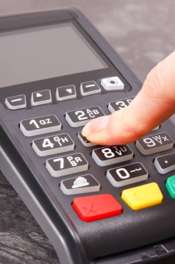 PIN kodunu ödeme terminaline giriş yapan bir kadın eli. Alışveriş için para ödemeden. Kredi kartı okuyucu. Finans kavramı