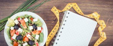 Feta peynirli taze Yunan salatası ve mezuralı not defteri. Zayıflama ve sağlıklı beslenme