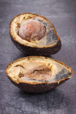 Koyu ahşap arka planda küf olan bir avokadonun iki yarısı. Sağlıksız yiyecekler