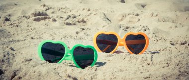 Kumsalda kumsalda renkli güneş gözlükleri. Güneş banyosu sırasında güneş koruması. Seyahat ve tatil zamanı kavramı