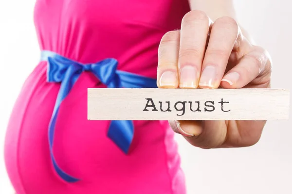 Kobieta Ciąży Ubrana Różową Sukienkę Niebieską Wstążką Napisem Sierpień Napisanym — Zdjęcie stockowe