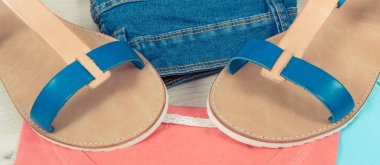 Kadınlar için şık ve rahat deri sandaletler, mavi kot pantolon ve kırmızı pamuklu gömlek veya kazak