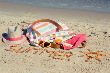 Yazın, kehribar taşı ve aksesuarlardan oluşan güneş şeklinde bir yazı. Rahatlamak için ya da kumsalda güneşlenmek için. Seyahat, turizm ve tatil zamanı kavramı