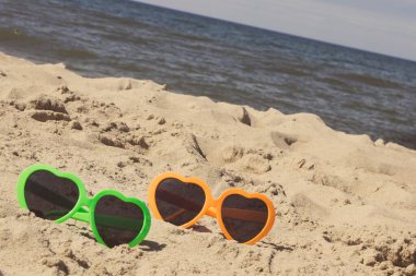 Kumsalda kumsalda renkli güneş gözlükleri. Güneş banyosu sırasında güneş koruması. Seyahat ve tatil zamanı kavramı