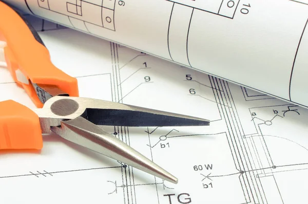 Electrical diagrams and metal pliers on construction drawing of house. Building home concept. Drawings for projects engineer jobs