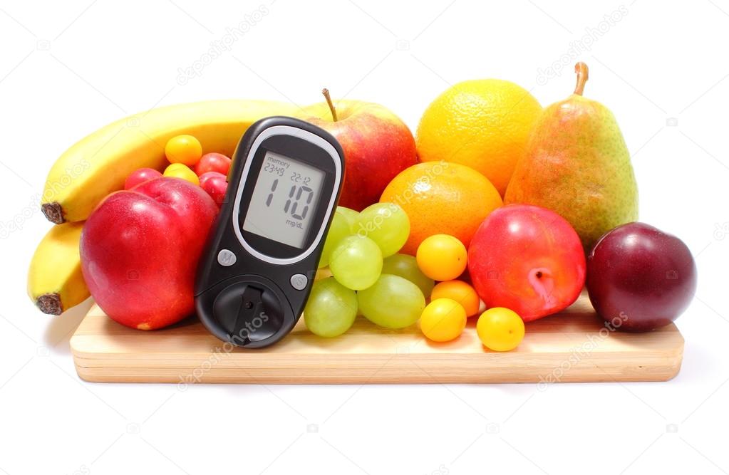 Glucose meter and fresh fruits on wooden cutting board
