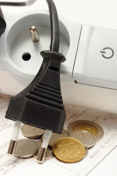 Electrical cords disconnected from power strip and electricity bill with coins — Stock Photo, Image