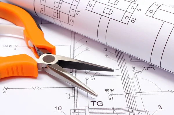 Metal pliers and rolled electrical diagram on construction drawing of house — Stock Photo, Image