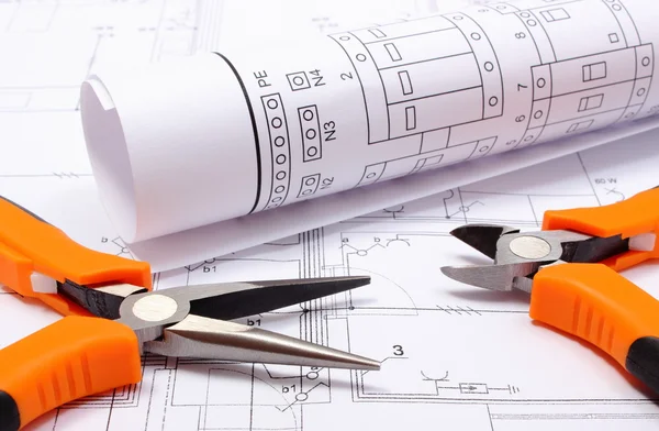 Metal pliers and rolled electrical diagram on construction drawing of house — Stock Photo, Image