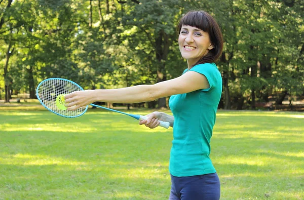 Mulher sorridente com raquete de badminton no parque de verão — Fotografia de Stock