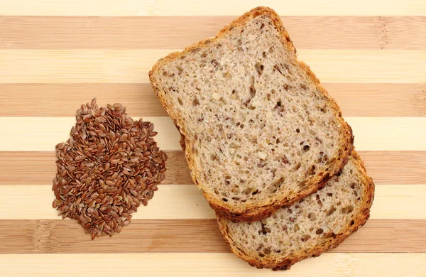 Linseed on cutting board and slices of wholemeal bread — Stock Photo, Image