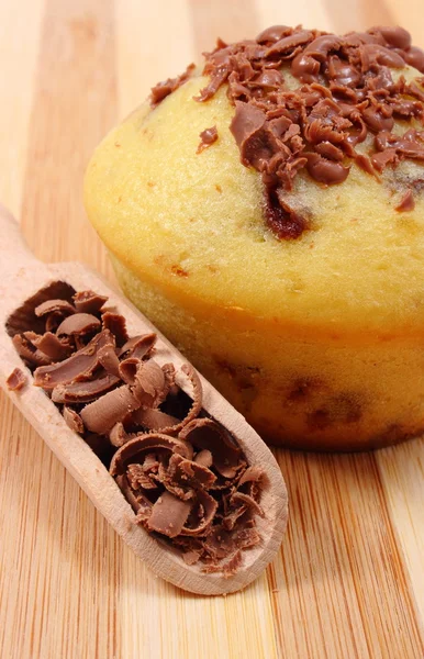 Fresh baked muffin and grated chocolate on wooden spoon — Stock Photo, Image