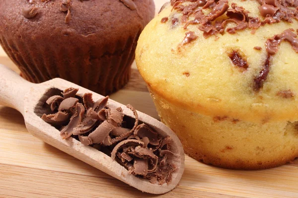 Fresh baked muffins and grated chocolate on wooden spoon — Stock Photo, Image