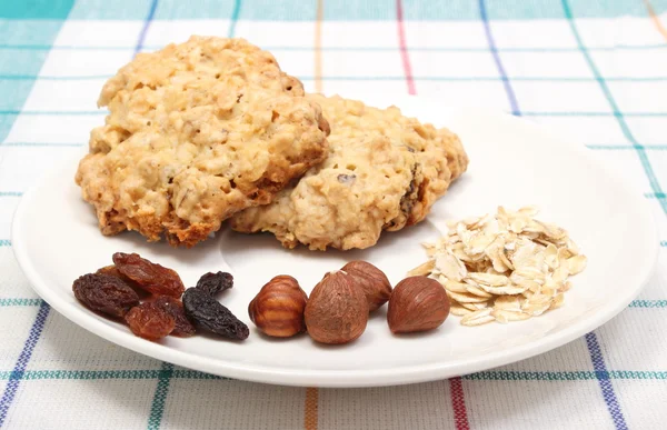 Oatmeal cookies with ingredients on white plate — Stock Photo, Image