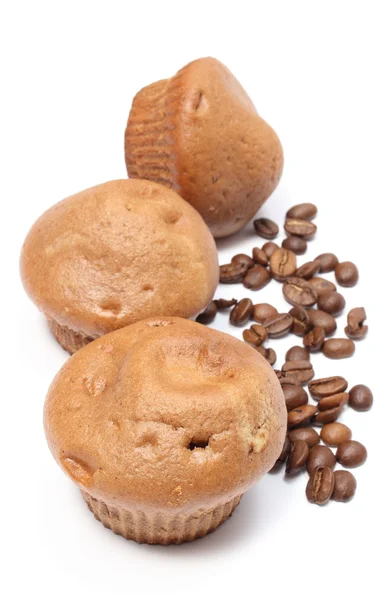 Muffins frescos assados e grãos de café em fundo branco — Fotografia de Stock