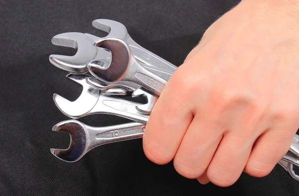 Hand of woman with wrenches on black background — Stock Photo, Image