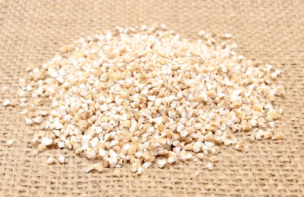 Heap of barley groats on jute canvas — Stock Photo, Image