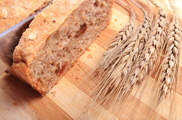 Slicing fresh bread, ears of wheat — Stock Photo, Image