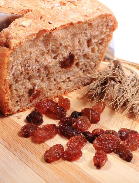 Snijden vers brood, oren van tarwe en rozijnen — Stockfoto