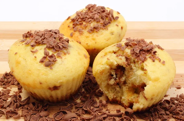 Fresh baked muffins and grated chocolate on wooden cutting board — Stock Photo, Image