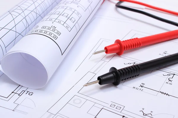 Rolled electrical diagrams and cables of multimeter on drawing of house — Stock Photo, Image