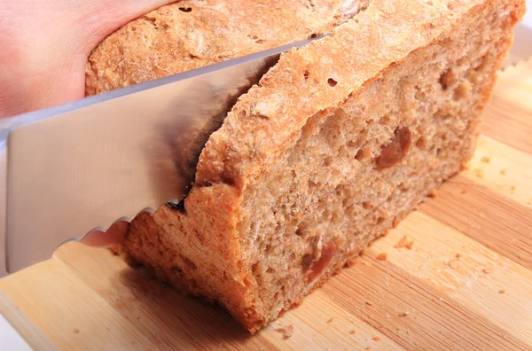 Hand of woman slicing fresh baked bread — Stock Photo, Image