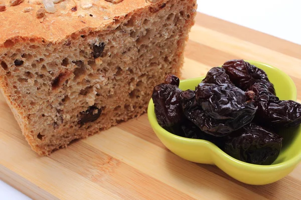 Gebakken volkoren brood en heap van gedroogde pruimen — Stockfoto