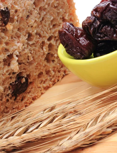 Pan integral al horno, ciruelas secas y espigas de trigo — Foto de Stock