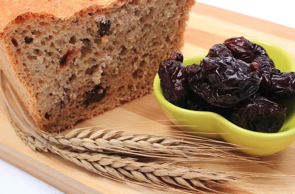 Gebakken volkoren brood, gedroogde pruimen en oren van tarwe — Stockfoto