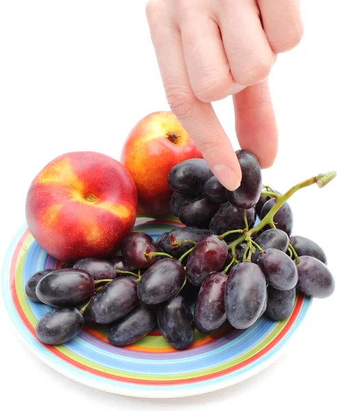 Mão e frutas no prato colorido — Fotografia de Stock