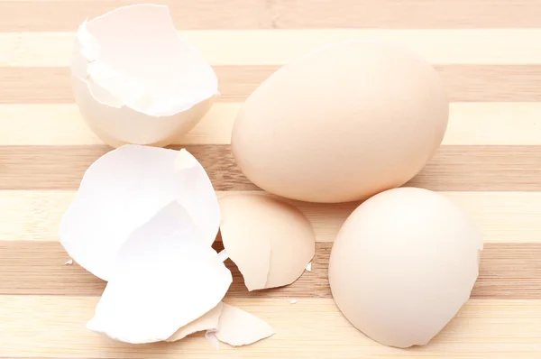 Fresh egg and cracked eggshell on wooden background — Stock Photo, Image