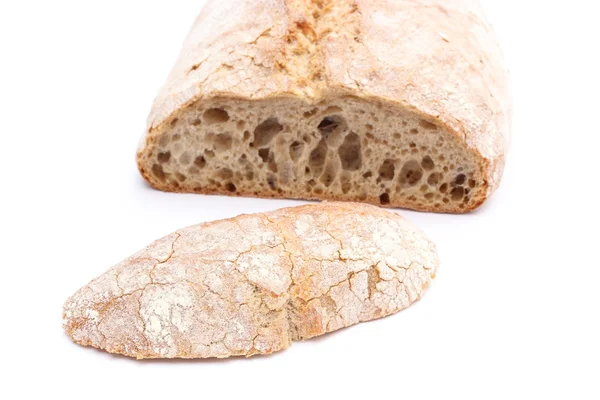 Slice of rye bread and loaf in background — Stock Photo, Image