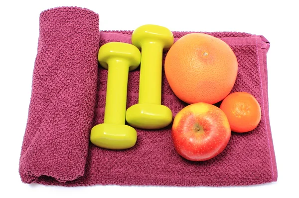 Fresh fruits and green dumbbells on purple towel — Stock Photo, Image