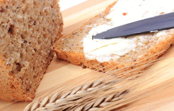 Rebanada de pan con mantequilla y espigas de trigo — Foto de Stock
