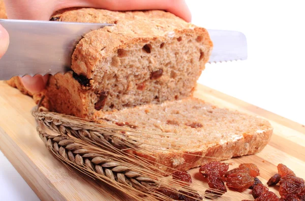 Snijden vers brood, oren van tarwe en rozijnen — Stockfoto