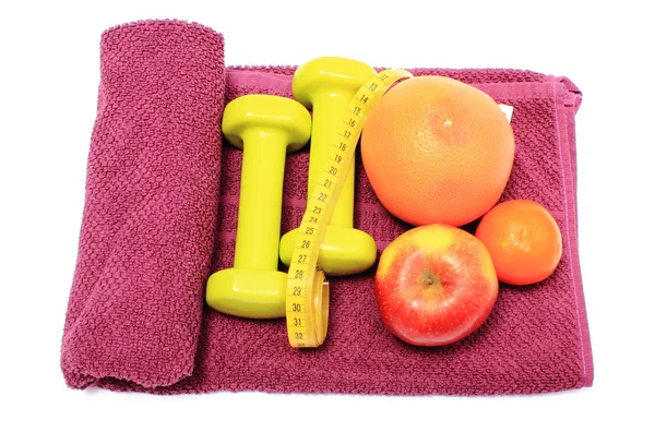 Fresh fruits, tape measure and green dumbbells on purple towel — Stock Photo, Image