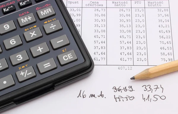 Miniräknare och penna liggande på kalkylblad — Stockfoto