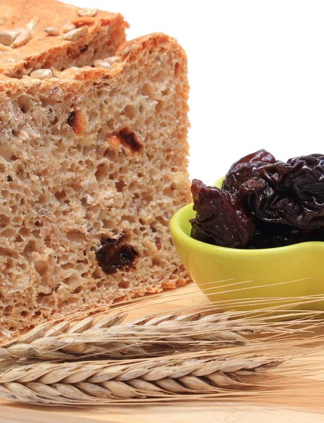 Gebakken volkoren brood, gedroogde pruimen en oren van tarwe — Stockfoto