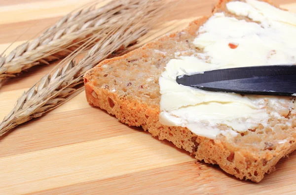 Dilim ekmek ve tereyağı ve buğday kulakları ile — Stok fotoğraf