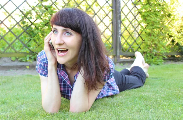 햇볕이 잘 드는 정원에서 휴대 전화와 함께 웃는 여자 — 스톡 사진