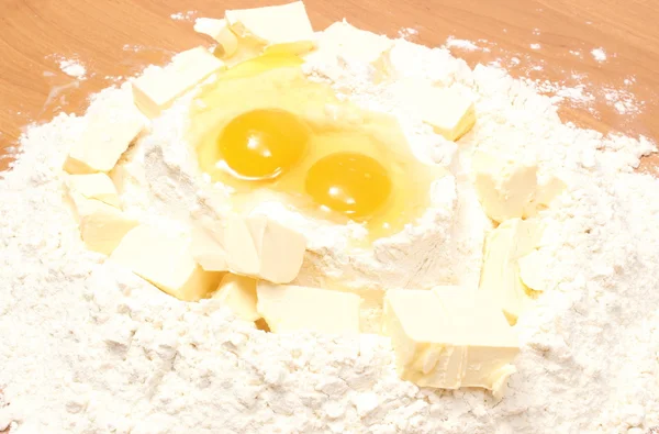 Ovos partidos em farinha e cubo de margarina na mesa — Fotografia de Stock