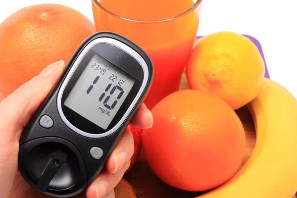 Hand med Glukometer, naturliga frukter, glas saft — Stockfoto