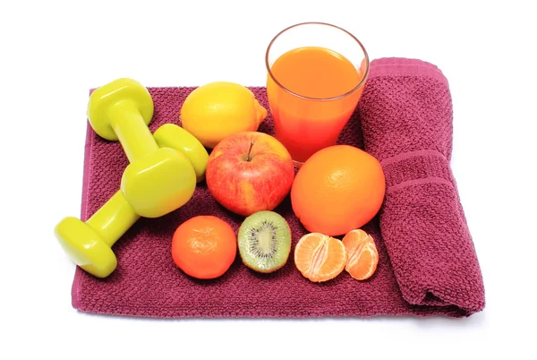 Frisches Obst, ein Glas Saft und Hanteln auf lila Handtuch — Stockfoto