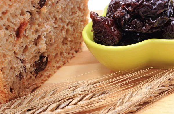 Pan integral al horno, ciruelas secas y espigas de trigo — Foto de Stock
