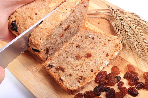 Snijden vers brood, oren van tarwe en rozijnen — Stockfoto