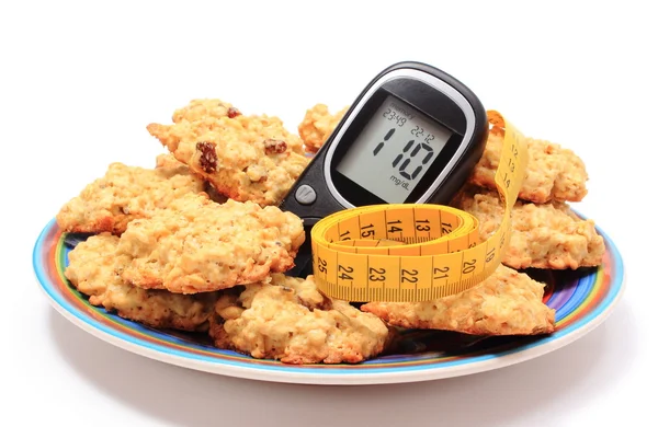 Glucometer, oatmeal cookies and tape measure on colorful plate — Stock Photo, Image