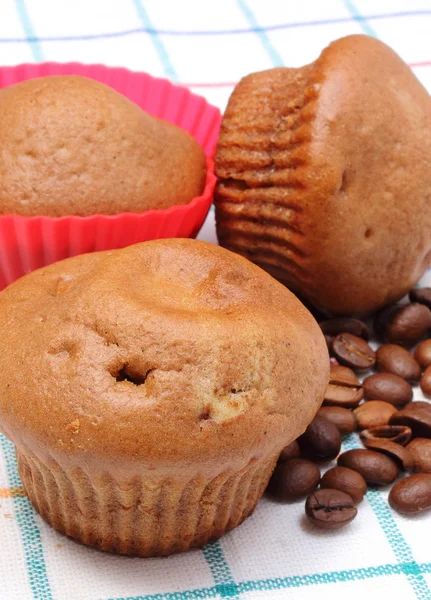 Frisch gebackene Muffins und Kaffeekörner auf buntem Tuch — Stockfoto