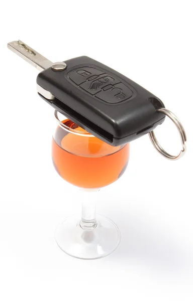 Car key lying on glass of wine. White background Stock Photo